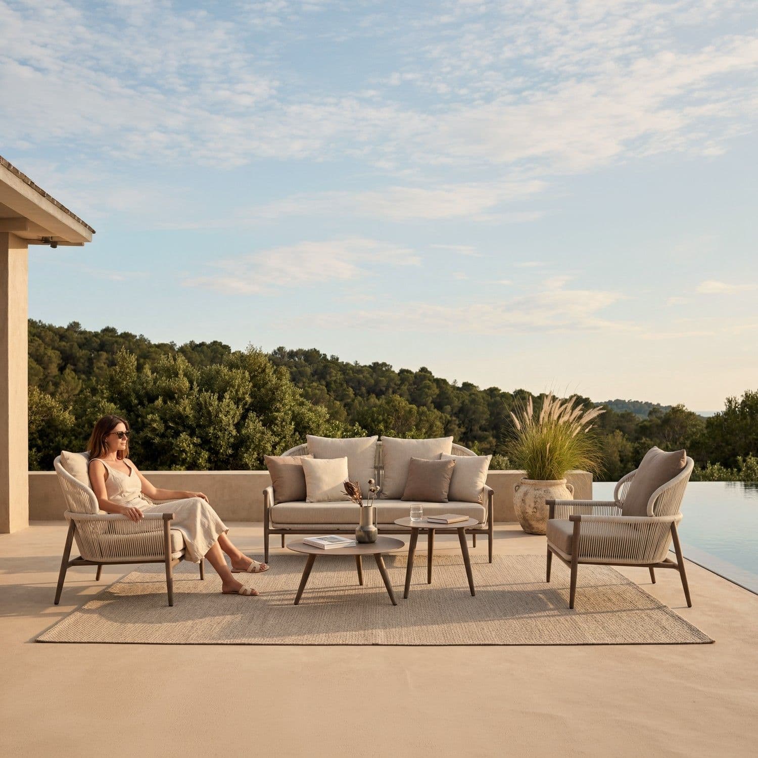 BLOOM Nest mobiliario de exterior de lujo en una terraza con piscina. Sillas y sofá trenzados, mesas premium para un estilo d