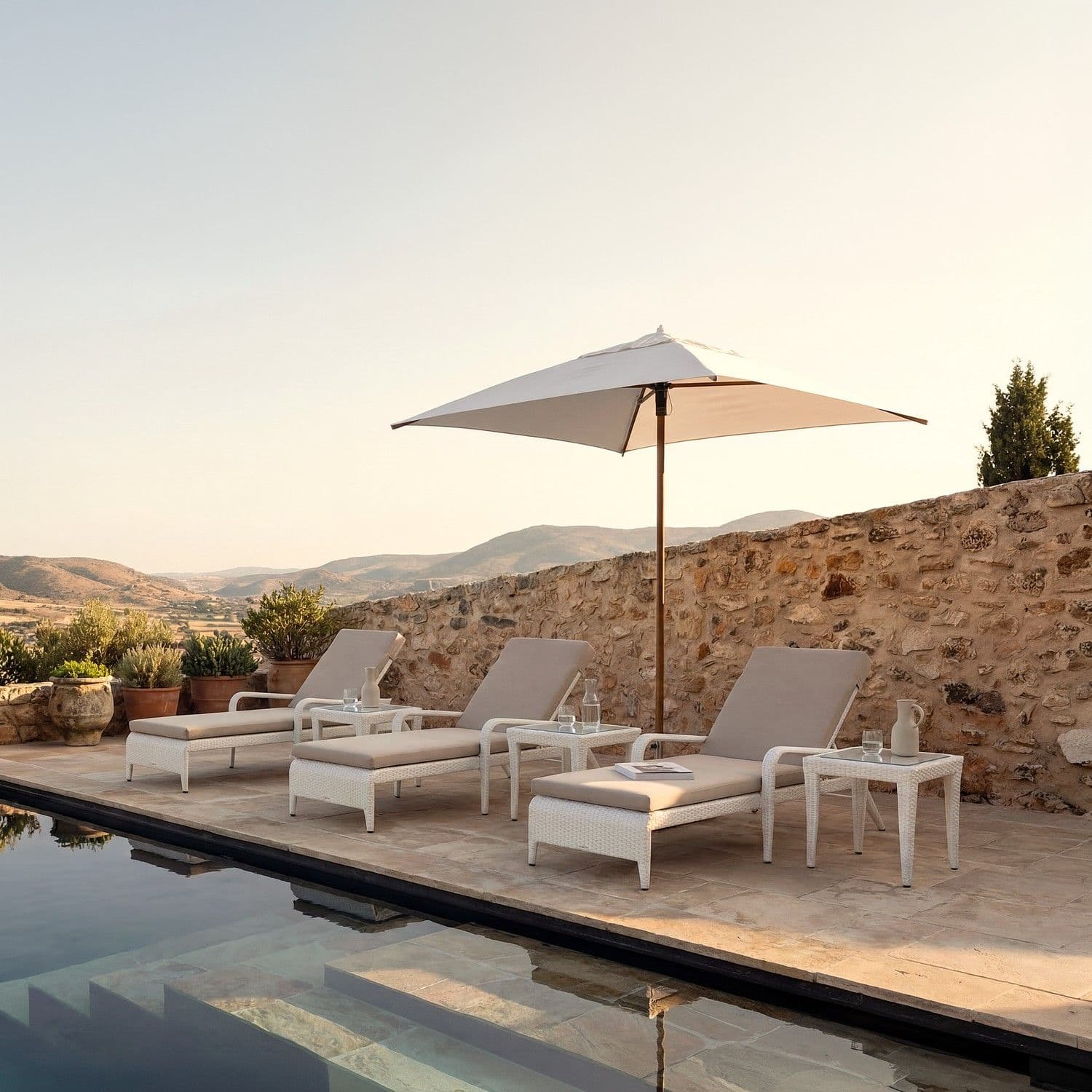 BLOOM Milan muebles de exterior de lujo: tumbonas trenzadas y mesas auxiliares en una terraza de piscina premium.